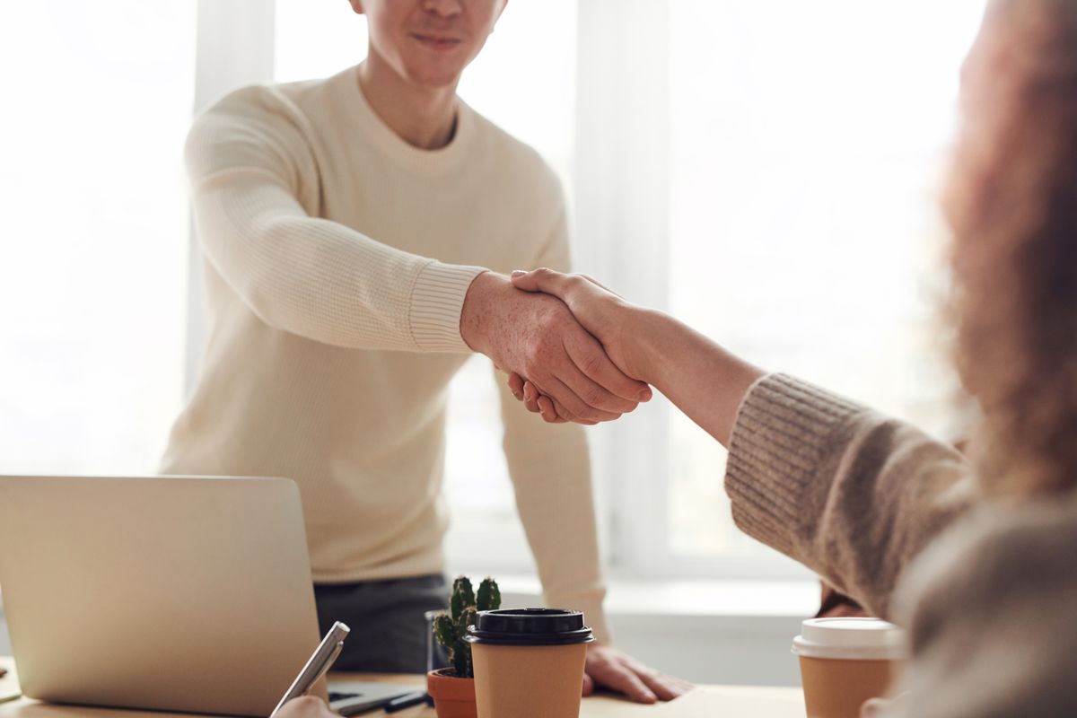 Two people shaking hands across a desk