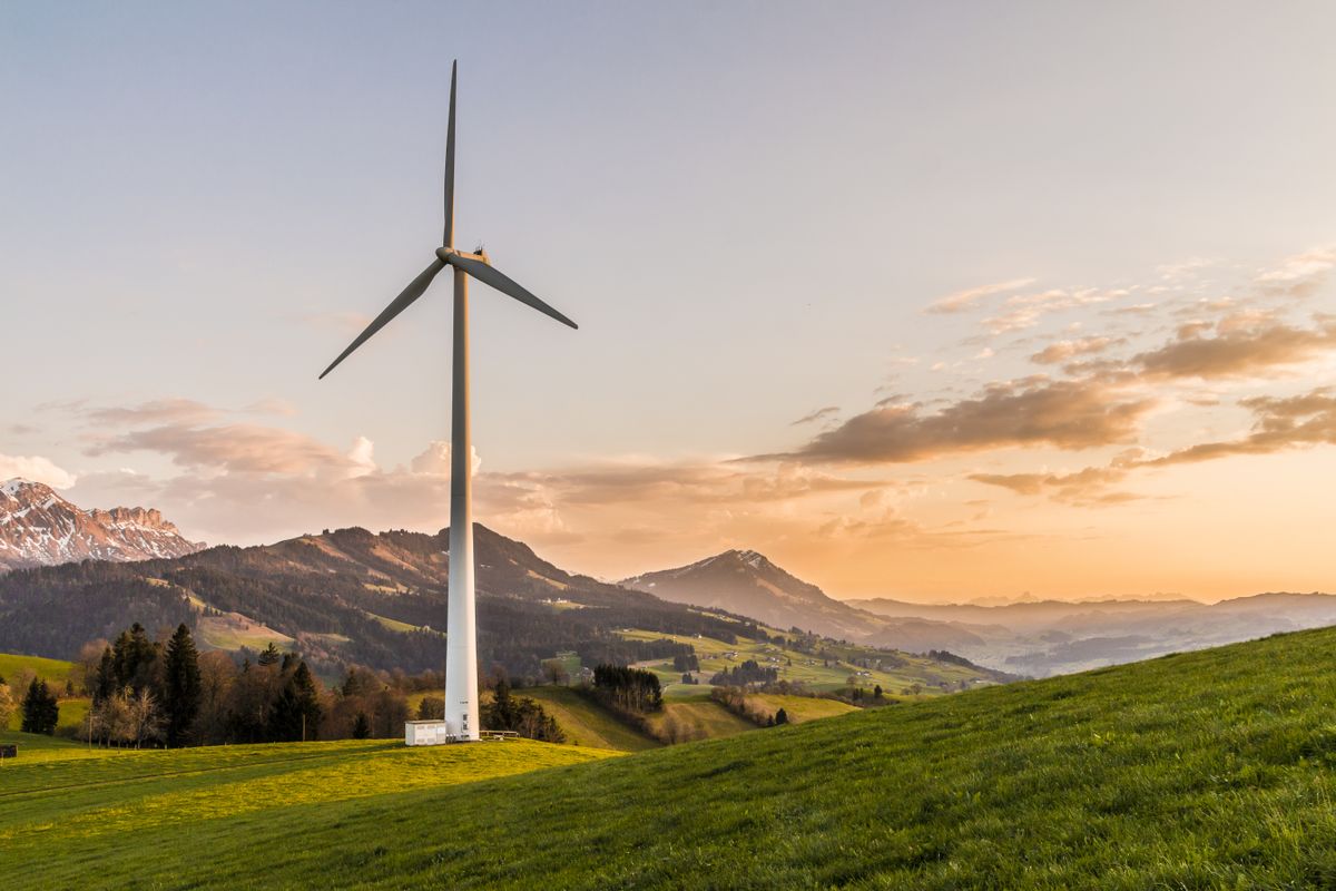 A wind turbine on a hillside at sunset